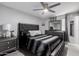 Modern bedroom featuring a black bed with luxurious bedding and a stylish ceiling fan at 6701 W Catalina Dr, Phoenix, AZ 85033