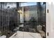 Modern bathroom featuring dark tile, glass shower enclosure, and soaking tub at 7327 E La Junta Rd, Scottsdale, AZ 85255
