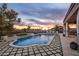 Inviting pool area with waterfall feature, lounge chairs, and lush landscaping at sunset at 7327 E La Junta Rd, Scottsdale, AZ 85255