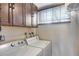 Bright laundry room features a white washer and dryer, dark wood cabinets, and natural light from window at 8225 N Central Ave # 44, Phoenix, AZ 85020