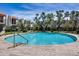 Community pool surrounded by a stone deck and black metal fence with mature trees providing shade at 8225 N Central Ave # 44, Phoenix, AZ 85020