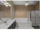 A full bathroom features a large mirror, soaking tub, walk-in shower, and neutral colors at 843 E Vera Ln, Tempe, AZ 85284