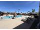 Outdoor community pool with lounge chairs, palm trees, umbrellas, and clear blue sky at 9302 E Broadway Rd # 49, Mesa, AZ 85208
