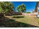 The backyard features a large grassy area and block fence for privacy and security at 9438 E Plana Ave, Mesa, AZ 85212