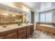 This primary bath features dual sinks, a soaking tub, wood-look flooring and a step-in shower with custom tile at 10539 E Corbin Ave, Mesa, AZ 85212
