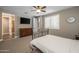 Comfortable bedroom features neutral colors, ceiling fan, television, and white-shuttered window for ample natural light at 10539 E Corbin Ave, Mesa, AZ 85212