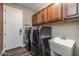 Functional laundry room boasts a utility sink, sleek dark appliances, and storage cabinets for added convenience at 10539 E Corbin Ave, Mesa, AZ 85212