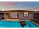 Inviting backyard pool featuring travertine tile, patio seating, and beautiful sunset views at 11357 E Unger Ave, Mesa, AZ 85212