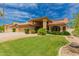 Well-maintained single Gathering home featuring lush green lawn and desert landscaping, terra cotta tile roof, and 3-car garage at 1590 W Desert Broom Dr, Chandler, AZ 85248