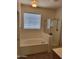 Bright bathroom showcasing a bathtub with window and a glass-enclosed shower at 15951 W Yavapai St, Goodyear, AZ 85338