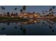 Stunning exterior view of the clubhouse reflecting on a tranquil lake at dusk, surrounded by palm trees at 1642 E Palm Beach Dr, Chandler, AZ 85249