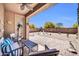 View of the covered patio with outdoor seating and a view of the spacious backyard area under a bright blue sky at 16593 W Alameda Rd, Surprise, AZ 85387