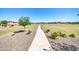 A beautiful walking path runs through a grassy green common area with houses on the horizon under a cloudless, vibrant blue sky at 16593 W Alameda Rd, Surprise, AZ 85387