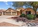 Inviting single-story home with a spacious three-car garage, desert landscaping, and mature shade trees at 16648 W Adams St, Goodyear, AZ 85338