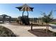 Community playground with covered play structure and gazebo offers fun and shade on a sunny day at 17677 W Odeum Ln, Goodyear, AZ 85338