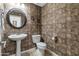 Half bath features decorative wall texture, pedestal sink, toilet, and framed round mirror at 18330 W Woodrow Ln, Surprise, AZ 85388
