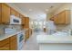 Open kitchen with white appliances, wooden cabinets, breakfast bar, and dining area in view at 19472 N Marble Canyon Ct, Surprise, AZ 85374
