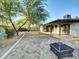 Spacious backyard, shaded by a large tree, including a patio area with shade covering, a fire pit, and a trampoline at 19604 N 13Th Ave, Phoenix, AZ 85027