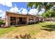 Spacious backyard featuring a covered patio, mature trees, and lush green grass at 23813 S Pleasant Way, Sun Lakes, AZ 85248