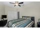 Well-lit bedroom with ceiling fan, white closet doors, and a bed with a patterned blanket on carpeted flooring at 23813 S Pleasant Way, Sun Lakes, AZ 85248