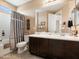 Bathroom with double sink vanity, decorative mirror, bath and shower with silver curtain, and tiled floor at 25540 N 103Rd Dr, Peoria, AZ 85383
