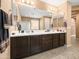 Bathroom with a spacious double vanity, dark wood cabinets, and a large mirror reflecting the shower at 25540 N 103Rd Dr, Peoria, AZ 85383