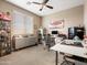 Well-lit bedroom boasts a ceiling fan, large window, and desk space, creating an ideal home office environment at 25540 N 103Rd Dr, Peoria, AZ 85383