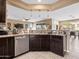 Modern kitchen area with granite countertops, stainless steel dishwasher, dark wood cabinets, and pendant lighting at 25540 N 103Rd Dr, Peoria, AZ 85383