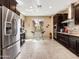 Bright kitchen with dark wood cabinets, tiled flooring, stainless steel refrigerator, and breakfast bar seating at 25540 N 103Rd Dr, Peoria, AZ 85383
