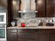 Kitchen close up showcasing granite countertops, dark cabinetry, stainless steel hood, and decorative backsplash at 25540 N 103Rd Dr, Peoria, AZ 85383