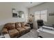 Cozy office space with a brown leather sofa, a mirror, natural lighting, and printer for a work-from-home environment at 25946 W Cat Balue Dr, Buckeye, AZ 85396