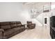 A bright living room with tile flooring, featuring a brown reclining sofa and view of the open staircase at 3134 E Mckellips Rd # 139, Mesa, AZ 85213