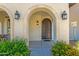 Covered porch with decorative sconces and an arched wooden front door at 3828 S Verbena Ave, Gilbert, AZ 85297