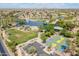 Beautiful aerial view of a neighborhood park with a lake, fountain, green spaces, and basketball court at 43612 W Chambers Ct, Maricopa, AZ 85138