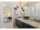 Bathroom featuring a dual vanity with black cabinets, granite counters, and views of the bedroom at 4812 E Daley Ln, Phoenix, AZ 85054