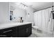 Bathroom with sleek, black vanity, marble countertop, decorative lighting, modern fixtures, and a walk-in shower with a shower curtain at 5004 W Kaler Dr, Glendale, AZ 85301