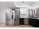 Bright kitchen featuring stainless steel appliances, dark cabinets, and a tiled floor at 5004 W Kaler Dr, Glendale, AZ 85301