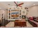 Cozy living room featuring a fireplace, custom built-ins, and a ceiling fan at 5511 N 128Th Dr, Litchfield Park, AZ 85340