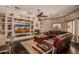 Comfortable living room with fireplace, built-ins, ceiling fan, and leather sofa at 5511 N 128Th Dr, Litchfield Park, AZ 85340