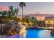 Backyard pool with a rock waterfall feature and a slide under a colorful sky at 5511 N 128Th Dr, Litchfield Park, AZ 85340