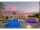 Beautiful outdoor pool with rock waterfall, palm trees, and hot tub at dusk at 5511 N 128Th Dr, Litchfield Park, AZ 85340
