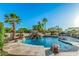 Gorgeous pool featuring a rock waterfall, slide, mature palm trees, and a covered area at 5511 N 128Th Dr, Litchfield Park, AZ 85340