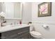 Cozy powder room featuring a marble vanity with grey cabinets, adorned with an orchid, and a framed picture at 621 W Desert Ave, Gilbert, AZ 85233