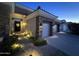 Well-lit home exterior featuring a stone facade, tile roofing, and a two-car garage, illuminated walkway, and inviting entrance at 621 W Desert Ave, Gilbert, AZ 85233