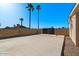 Large backyard featuring palm trees, a concrete parking pad, and a secure wooden fence at 6602 E Heather Dr, Mesa, AZ 85215