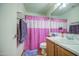 Functional bathroom features pink shower curtain, sink, and mirror, offering a clean and practical space at 703 N Redwood Ln, Buckeye, AZ 85326