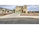 Tan two-story home with desert landscaping and a long driveway leading to a green garage door at 703 N Redwood Ln, Buckeye, AZ 85326