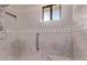 Shower featuring beige tiling, a showerhead, window, and a silver grab bar for accessibility at 7904 E Madero Ave, Mesa, AZ 85209