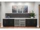 Modern bar area featuring black cabinetry, wine cooler, marble countertops, and stylish tile backsplash at 8501 E Appaloosa Trl, Scottsdale, AZ 85258