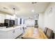 Bright open-concept living and kitchen with white cabinets, an island, and a wooden table at 9413 W Williams St, Tolleson, AZ 85353